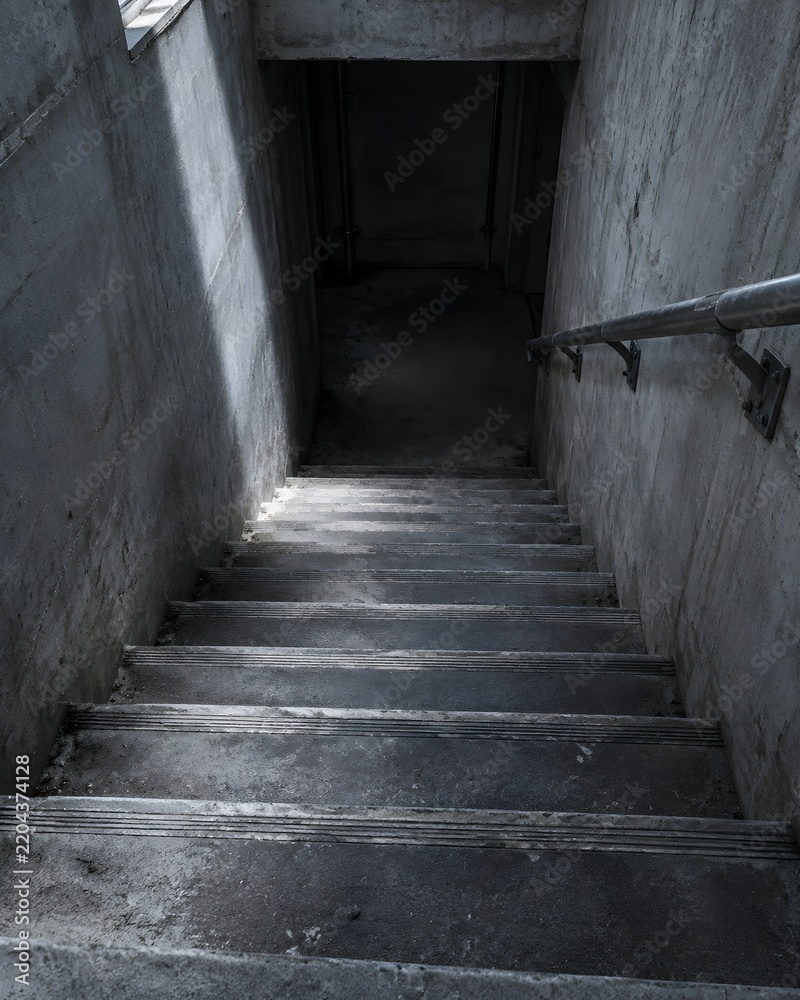 Fototapeta premium A concrete stairwell descending into a supply shelter with worn tread nosings