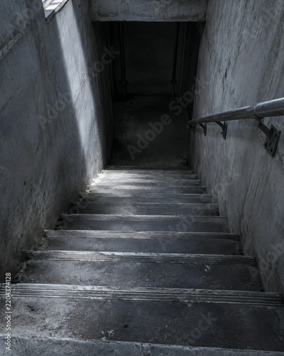 A concrete stairwell descending into a supply shelter with worn tread nosings