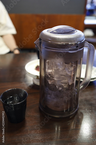 氷入りのお冷のピッチャーとコップ。飲食店の木製テーブル