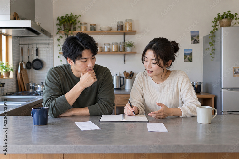 Fototapeta premium Couple reviewing shared household expenses together in their kitchen