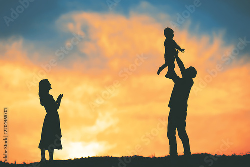 Family silhouette enjoys a vibrant sunset scene with a father lifting his child