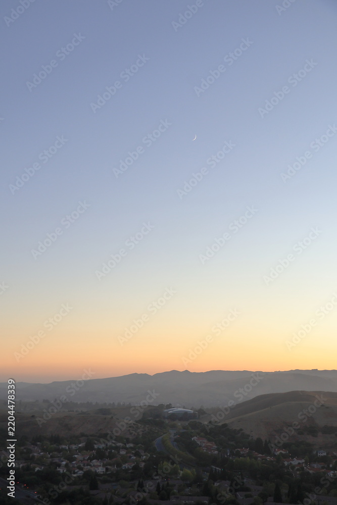 Fototapeta premium Crescent moon shines high above San Ramon valley at sunset