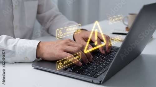 Person using laptop with glowing yellow cyber security warning icons