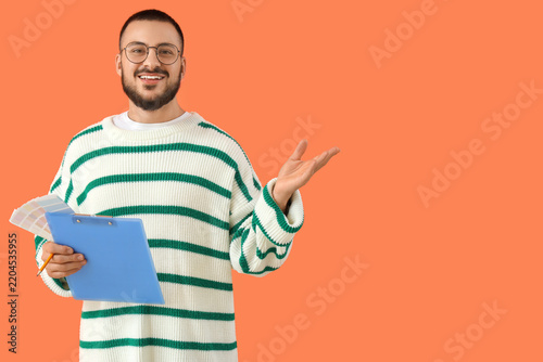 Male interior designer with clipboard on orange background