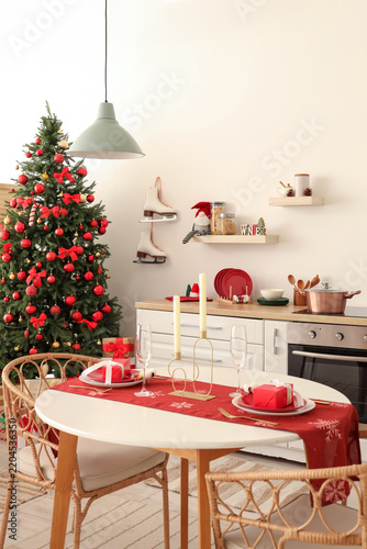 Interior of light kitchen with Christmas tree, dining table and shelves