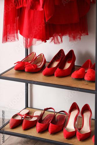 Stylish red female shoes on shelves in wardrobe, closeup