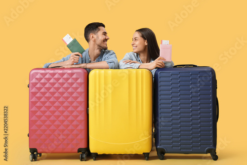 Beautiful young happy couple of tourists with passports, tickets and suitcase...