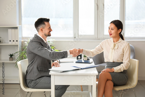 Human resources manager interviewing shaking hands with applicant in office