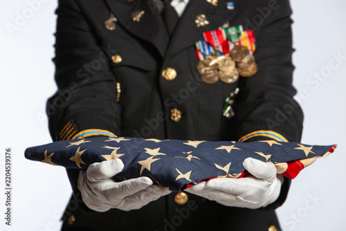 Military Officer in Dress Uniform Holding Folded American Flag with Medals