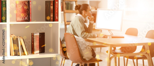 Remote learning and academic research, student studying on computer with book...