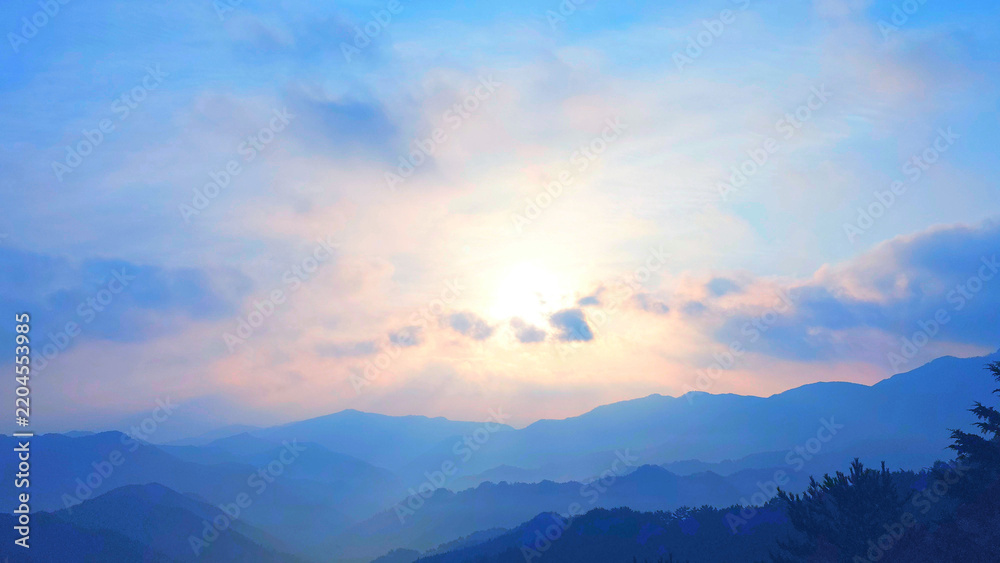 Fototapeta premium 雲間から光が差し込む山並みと夕空の風景
