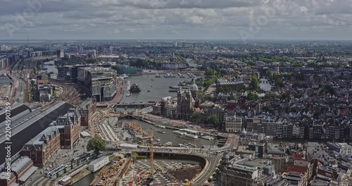 Amsterdam Netherlands Aerial v3 panning shot capturing historical urban downtown cityscape of binnenstad neighborhood with iconic central train station and water channel at daytime - August 2021