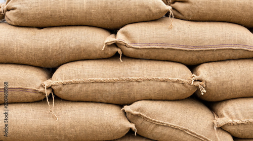 Close-up view of stacked burlap sandbags tied with rope, used as flood barriers and emergency protection