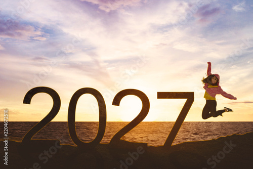 Energetic Woman Jumping Joyfully Beside Large 2027 Year Numbers at Sunset Sea