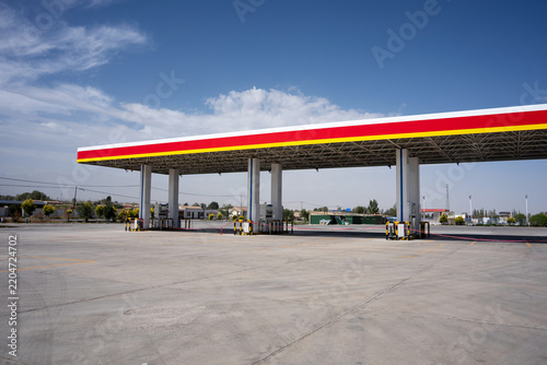 empty shell gas station with red and yellow canopy under blue sky