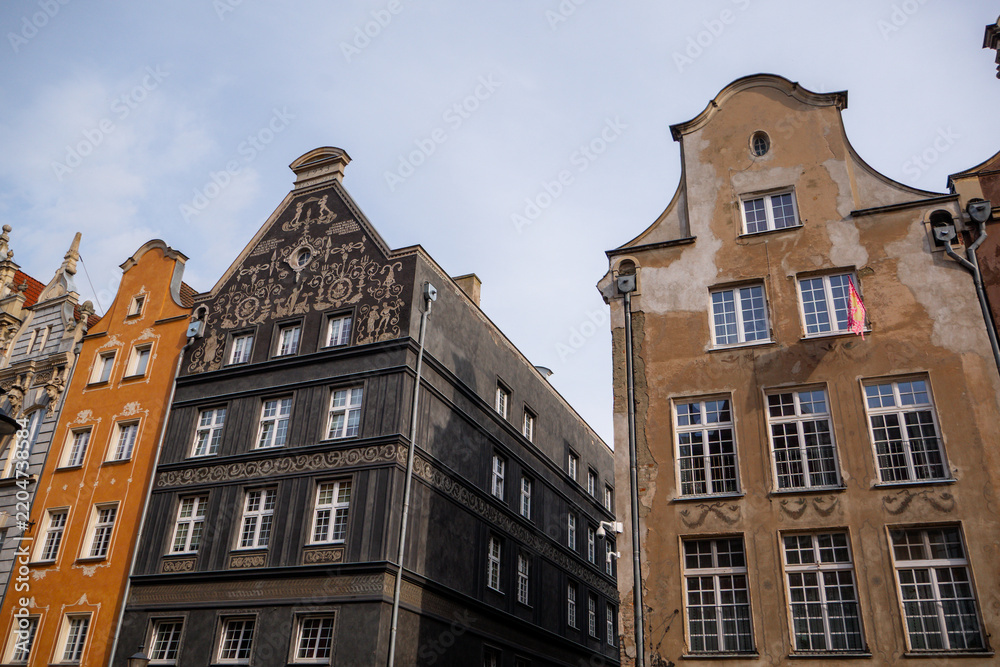 Obraz premium Low angle view of beautiful historic building facades with sgraffito wall art paintings and decorative gables in Gdansk Old Town Poland, traditional European hanseatic architecture and travel landmark
