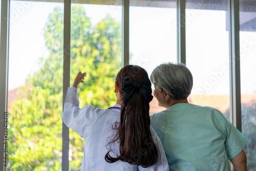 Doctor pointing to garden view beside senior woman patient