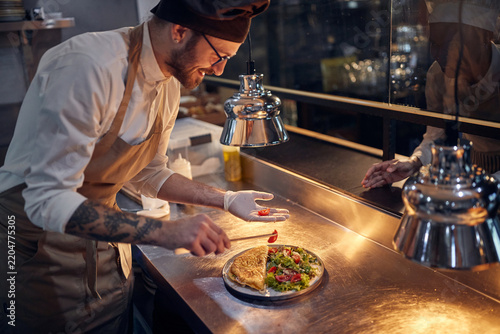 Cook in Professional Modern  kitchen, restaurant concept. Chef serving breakfast from eggs and salad.