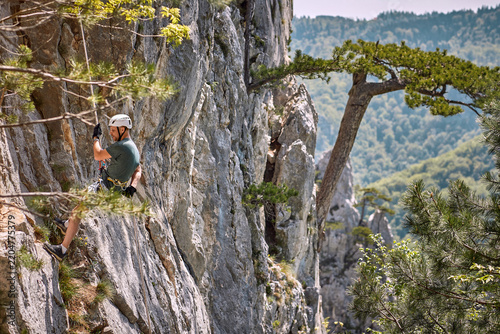 man with helmet climbing on mountain rocks with rope and equipment. Nature, advanture , sport concept.