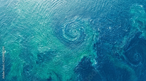 Aerial view of swirling ocean whirlpool, turquoise water vortex seen from above nature phenomenon.