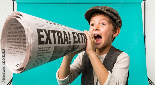 Young boy shouting through rolled newspaper like a newsboy, bright teal background, expressive face. Journalism, retro concept, childhood, media communications.