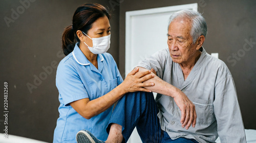 Caring nurse wearing mask helps elderly patient stand up with gentle support and compassion.