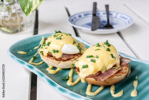 Eggs Benedict breakfast food on white table at modern restaurant cafe outdoors