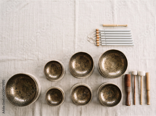 Arrangement of handmade brass Tibetan singing bowls and chimes on linen surface
