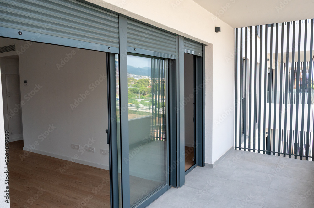 Fototapeta premium Modern apartment balcony with sliding glass doors and shutters