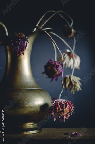 still life with withered flowers in brazen vase. Transcience concept