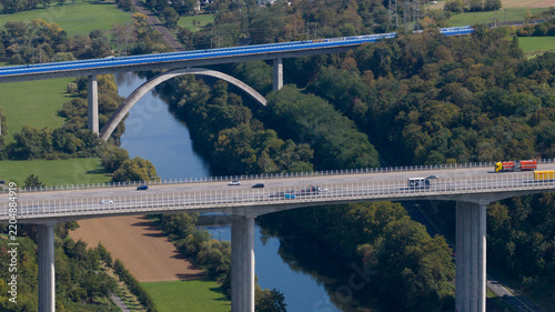Aerial view of the Lahn Valley Bridge spanning the river with cars driving across the highway in the green landscape of Limburg an der Lahn, Hessen, Germany.