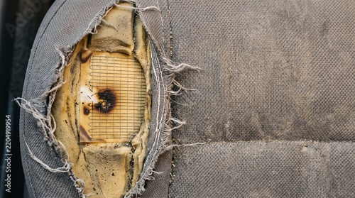 Damaged car seat upholstery with exposed foam and fabric tear