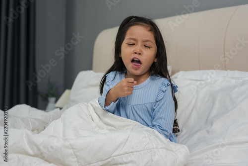 sick preschoool child girl coughing in bed with cold symptoms