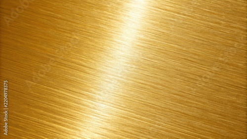 Brushed gold metal surface with diagonal reflections during bright studio lighting for luxury backgrounds