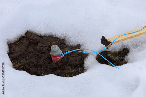 Canvastavla An explosive device, resembling a grenade, is installed in a muddy pit amidst snow cover