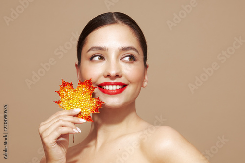 Portrait of beautiful young woman with autumn leafs. Healthy clean fresh skin natural make up beauty eyes