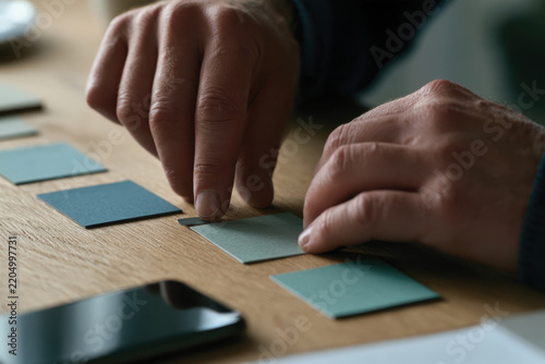 An intimate view of hands carefully aligning different shades of colored cards, emphasizing the attention to detail in sorting through ideas and methods for effective planning.