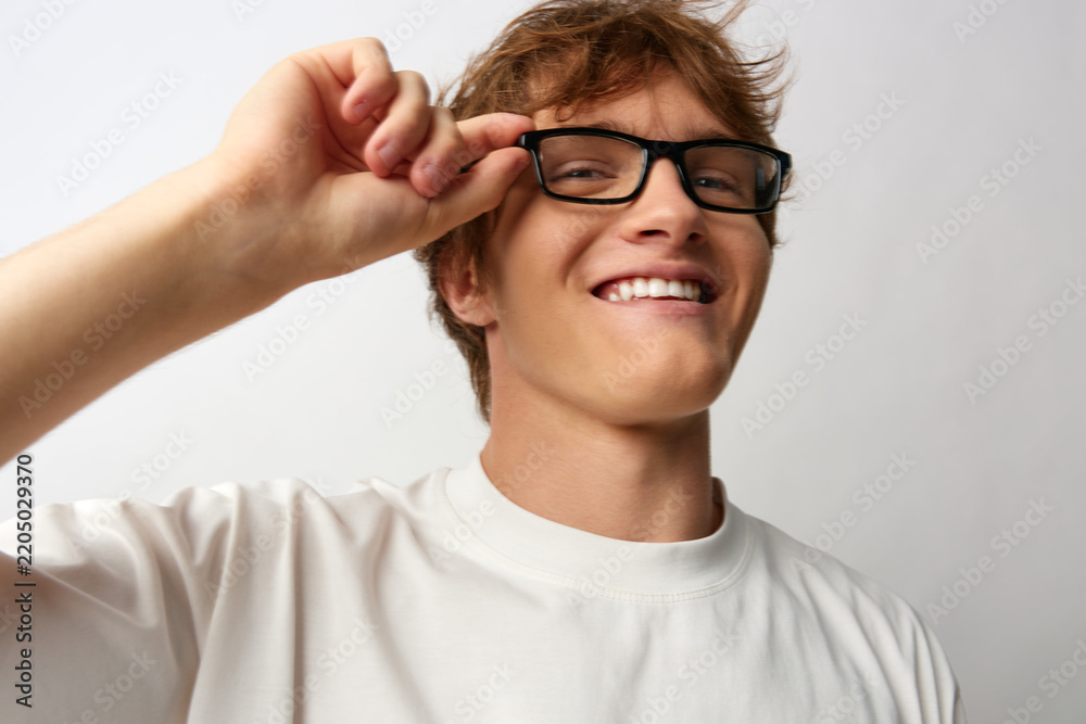 Fototapeta premium Young man with new glasses smiling cheerfully in studio. Concept of optician advertising and vision satisfaction. Relaxed pose with happy mood and clear vision.