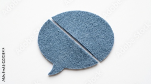 A blue felt speech bubble cutout is sliced diagonally into two pieces on a white studio background representing communication break