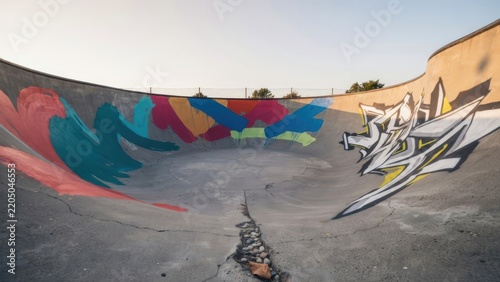 Empty concrete skatepark bowl with colorful graffiti street art mural