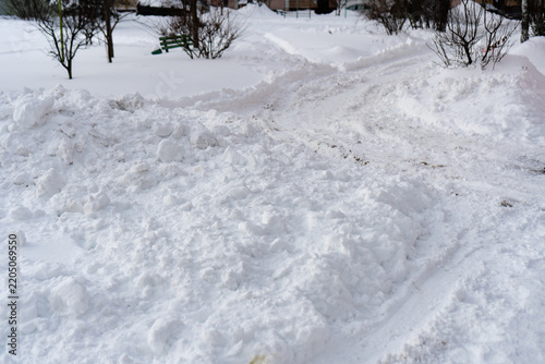 Path in the white snow with footprints on cold day. Photo of snow on the ground in the winter evening.