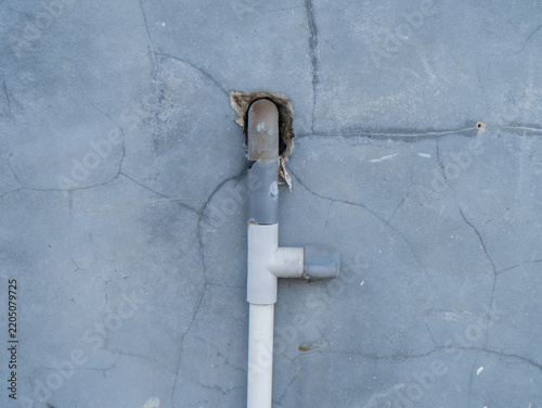 PVC Water Pipe Installation on Cracked Concrete Wall for Plumbing and Home Repair Concept