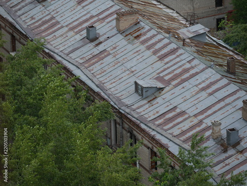 Weathered metal roof with rust patterns on an old building, showing aged architecture, material deterioration, restoration needs and urban heritage