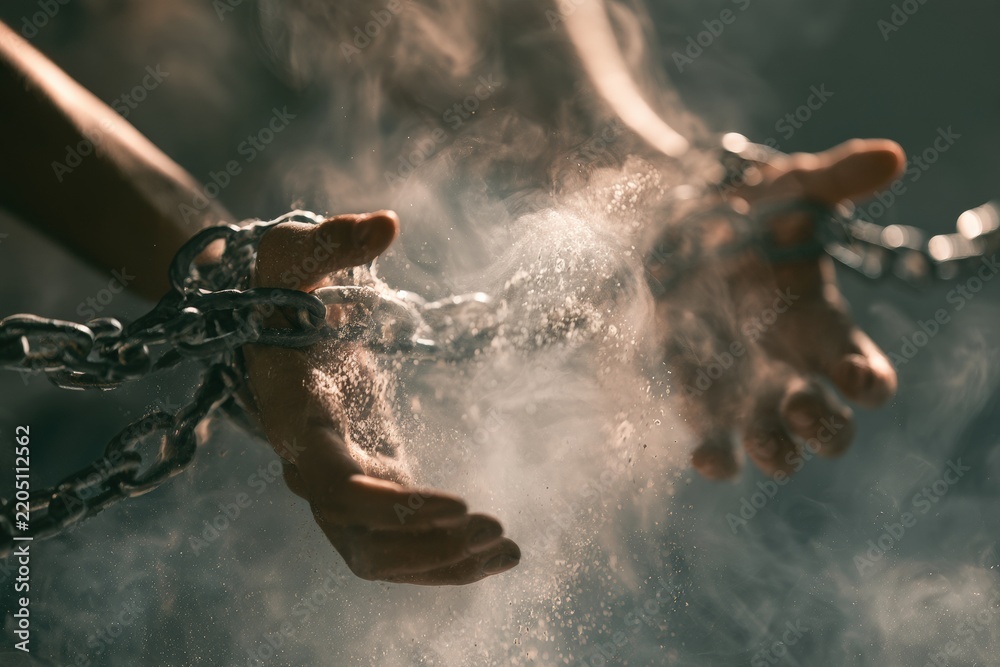 Obraz premium Hands breaking misty chains symbolizing release from mental burdens