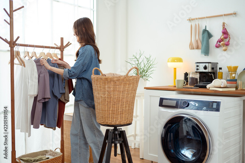 Asian Woman Hanging Clothes and Organizing Laundry at Home