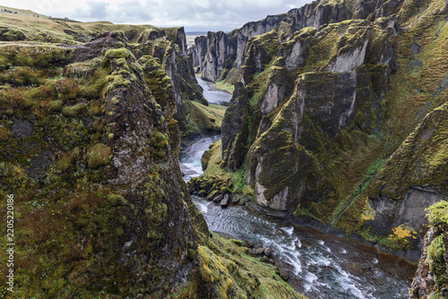 Moss covered rock walls rise above the winding Fjadra River in Fjadrargljufur canyon near Kirkjubaejarklaustur, South Iceland, with rapids threading through the narrow gorge.