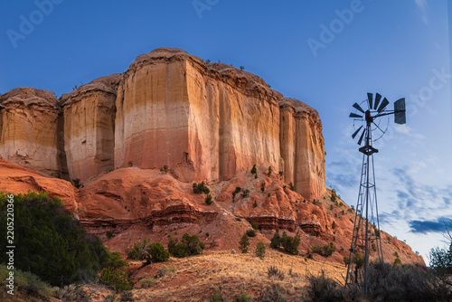Red buttes stand sentinel by an old windmill in the New Mexican desert.