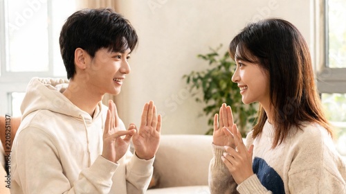 Happy Asian Couple Communicating Using Sign Language in Bright Cozy Living Room