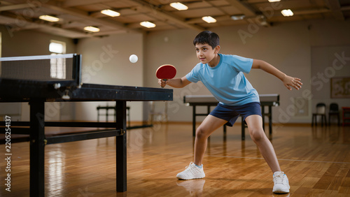 Focused Young Indian Boy Playing Table Tennis Match in Indoor Sports Academy Center Venue