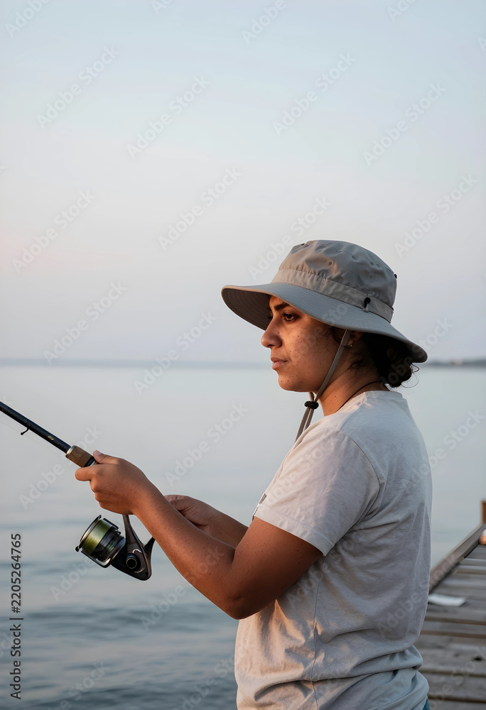 Fototapeta premium Mindfulness and leisure, woman fishing on a wooden pier at sunset for stress relief and outdoor recreation in a calm lake environment during summer